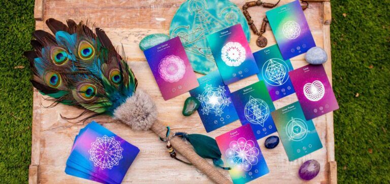 A collection of mystical tarot cards featuring geometric designs, peacock feathers, and healing crystals on a wooden surface.