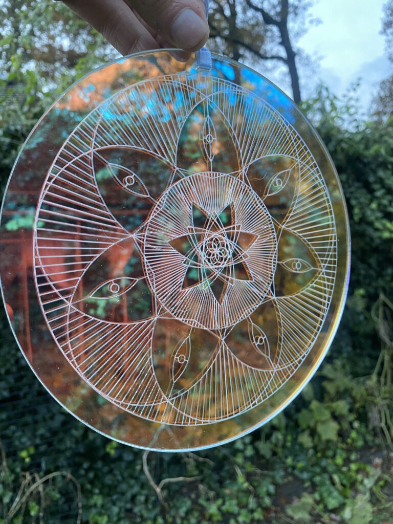 Ein detailliertes Glasmandala mit mehreren Augenmotiven und geometrischen Mustern, das aufwändige Handwerkskunst und design zeigt.