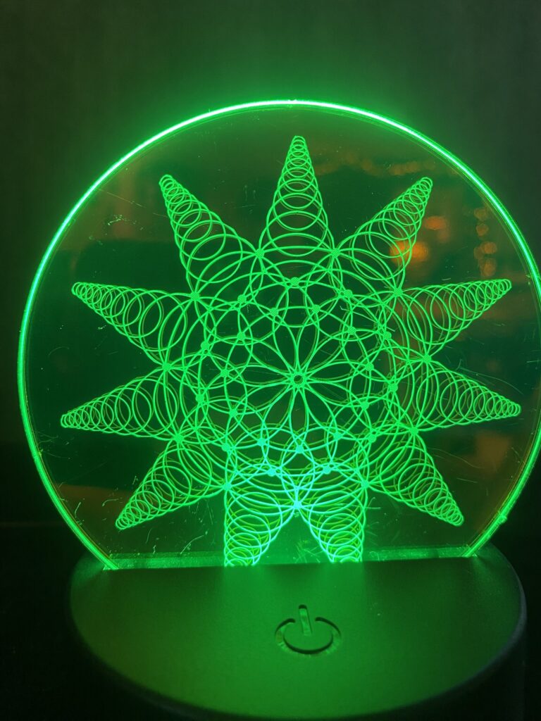 Green LED lamp featuring a geometric star pattern design, illuminated and showcasing intricate line work.