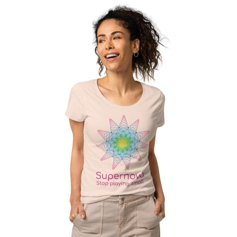 Women's beige t-shirt featuring a colorful Supernova graphic design with the text 'Stop playing small' in pink.